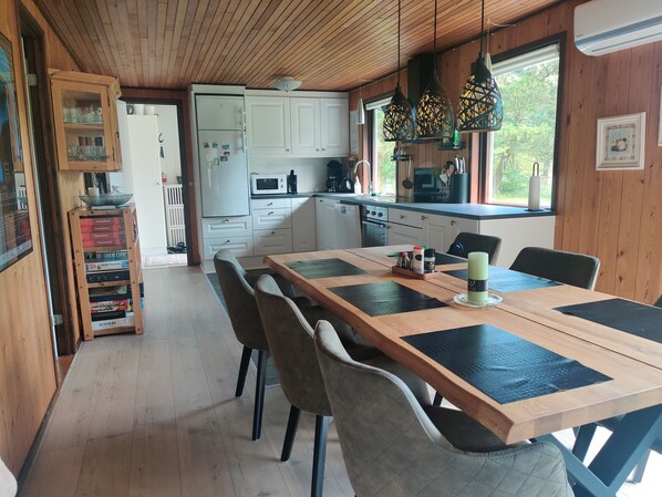 A wooden interior with a dining table, chairs, and a kitchen area.
