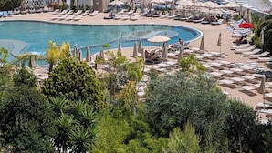 Un resort con piscina, zonas de descanso y vistas al mar.