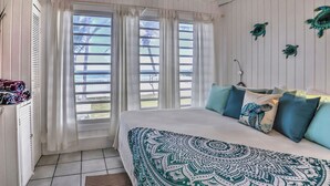 Une chambre à coucher avec un lit, des rideaux et une vue sur l’extérieur.