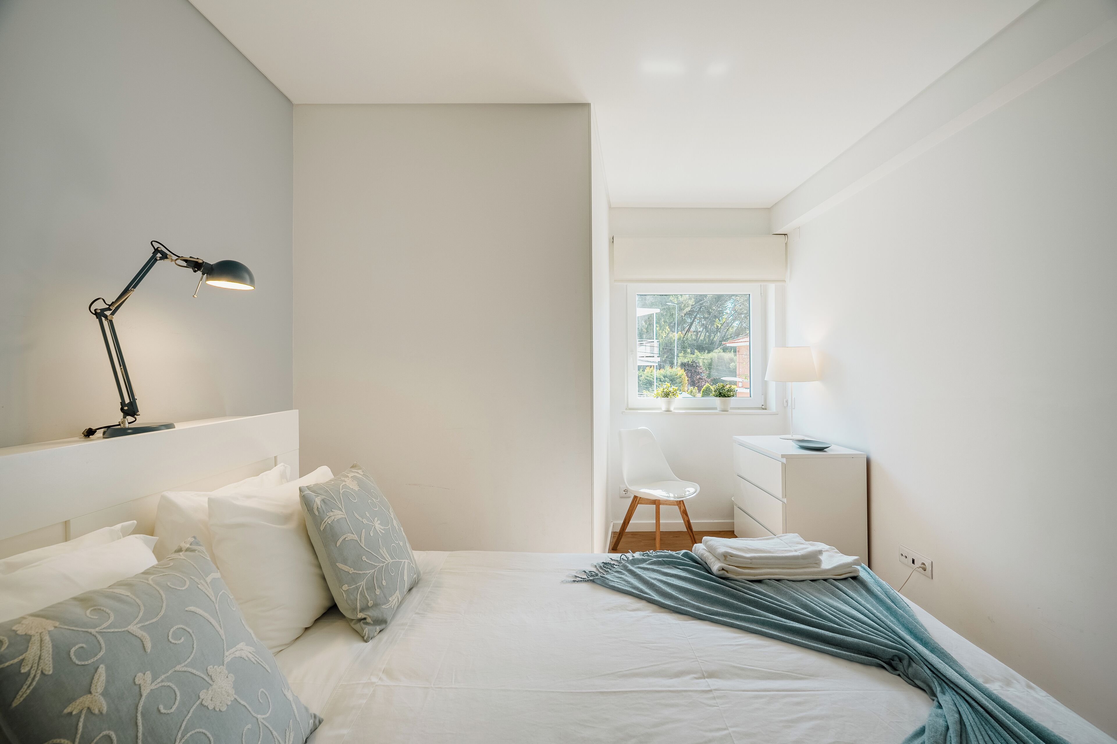 Ein Schlafzimmer mit Bett, Schreibtisch, Stuhl und Fenster.