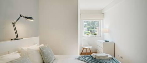 Ein Schlafzimmer mit Bett, Schreibtisch, Stuhl und Fenster.