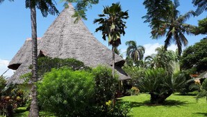 A thatched-roof structure surrounded by lush greenery and palm trees. - Luxurious villa w/pool,10min beach, 280m²,w/ personal & cook, Jacuzzi, A/C,wifi (Kenia)