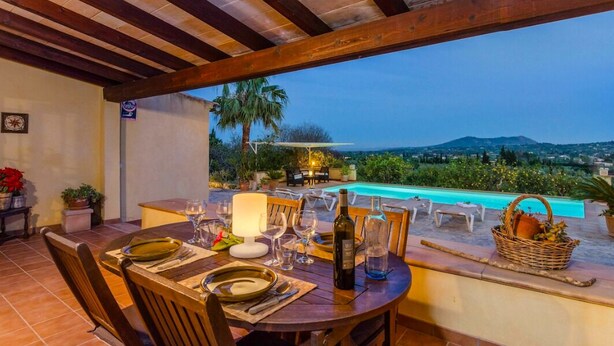An outdoor dining area with a view of a pool and mountains.