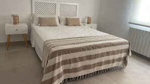 Une chambre bien rangée, avec un lit, deux tables de chevet, un radiateur et une fenêtre.