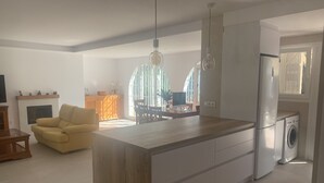 Une cuisine moderne dotée d’un îlot central, d’un coin repas avec un canapé et d’une grande fenêtre qui laisse entrer la lumière naturelle.