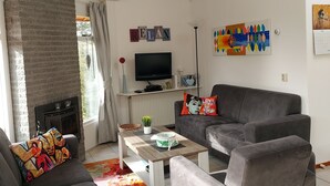 A modern living room with a fireplace, grey sofas, a coffee table, and a flat-screen TV.