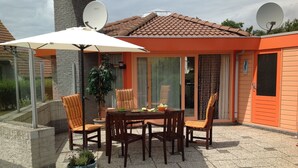 An outdoor patio with a table and chairs, a potted plant, and a satellite dish.