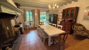 A kitchen with a dining table, chairs, a chandelier, and a fireplace.