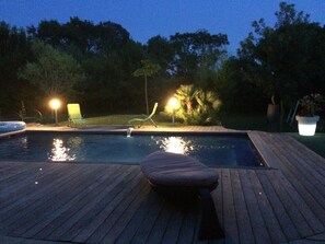 A swimming pool with a wooden deck, surrounded by trees and equipped with outdoor lighting. - beautiful property in the Aix countryside (Aix-En-Provence)