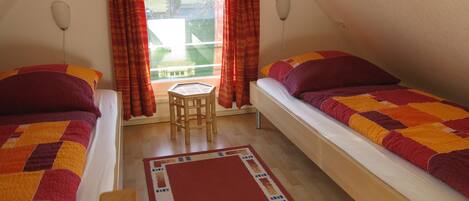A room with two beds, a small table, and a window with curtains.