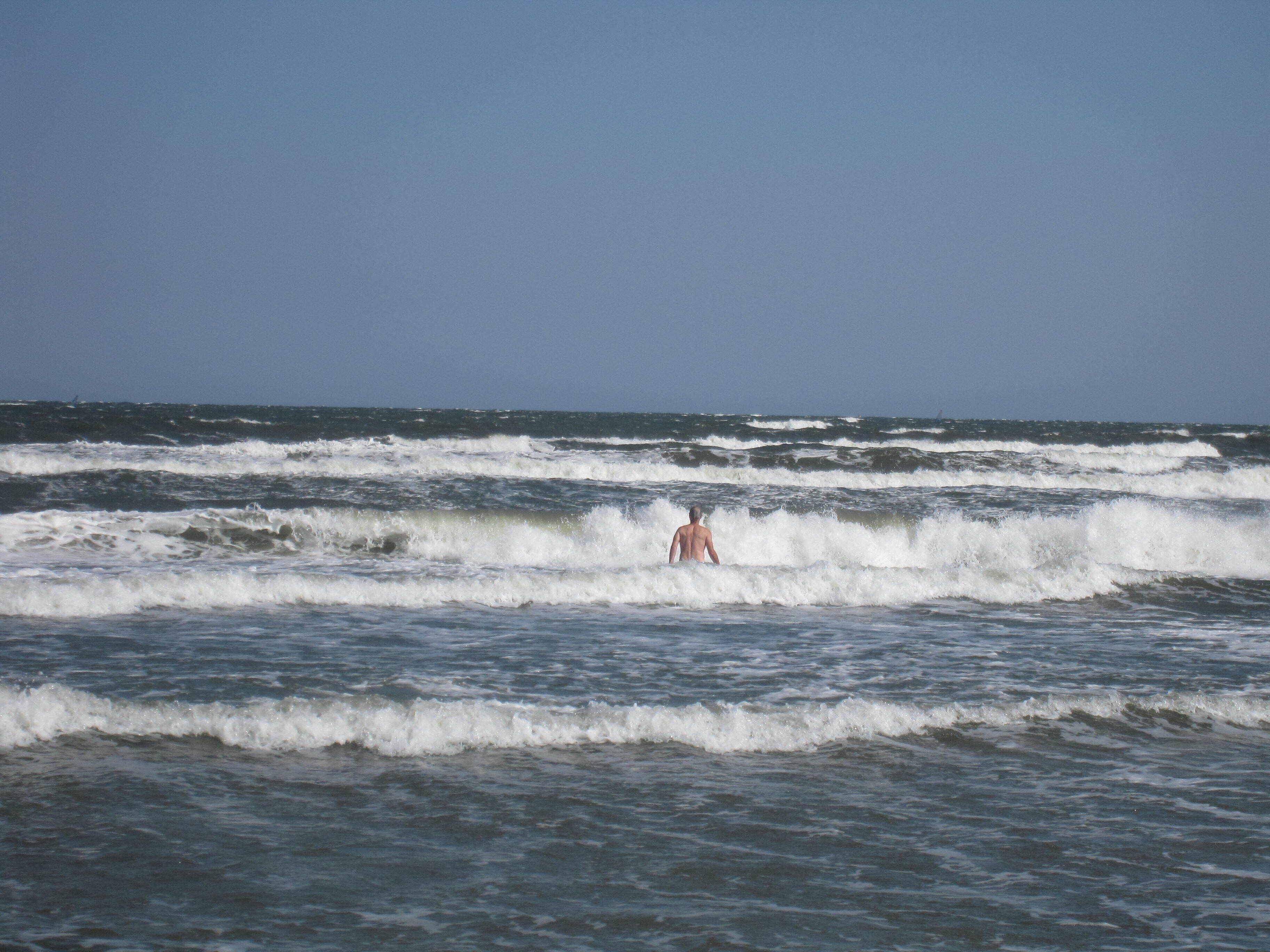 A beach scene with waves and a person in the water.
