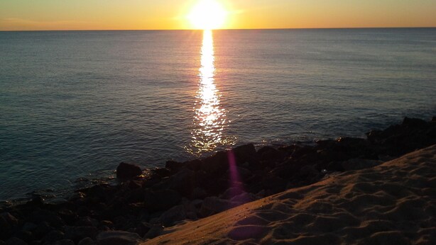 A sunset over a calm sea with a rocky shoreline. - fully equipped apartment on the first floor (capbreton)