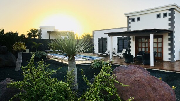 A modern building with a pool, surrounded by rocks and greenery.