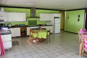 Cocina compacta con armarios blancos, microondas y estufa. Hay una mesa de comedor con sillas y una pequeña alfombra.