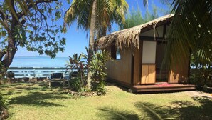 A small wooden structure with a thatched roof, a porch, and a view of the ocean.