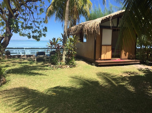 A small wooden structure with a thatched roof, a porch, and a view of the ocean.