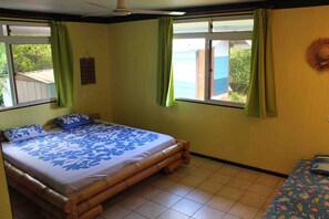 Una habitación con cama, una ventana con cortinas, una mesita y un sombrero colgado en la pared.