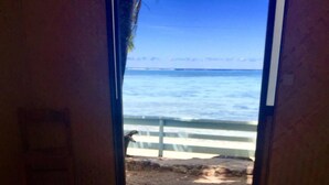 A room with a bed, a window, and a view of the beach.