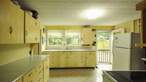 A compact kitchen with yellow cabinets, a sink, and a refrigerator. - Howard Family Cottage with Casco Bay Sunset Views! (Harpswell)
