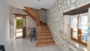 Un escalier avec des murs en pierre et des marches en bois menant à un deuxième étage.