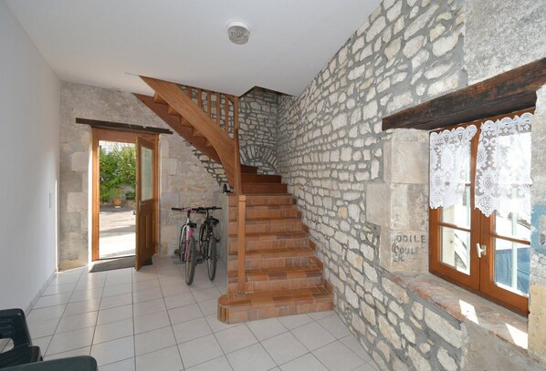 Una escalera con paredes de piedra y escalones de madera que sube a un segundo piso.