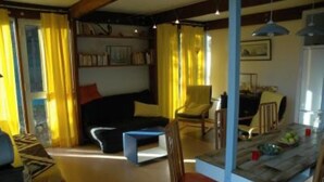 Ein gemütliches Wohnzimmer mit Sofa, Couchtisch und Essbereich mit Tisch und Stühlen.