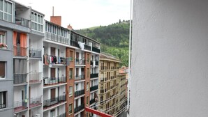 Un edifici residencial de diverses plantes amb balcons, una vista al carrer i una barana vermella.