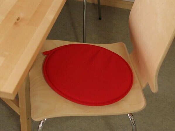 A wooden chair with a red cushion.
