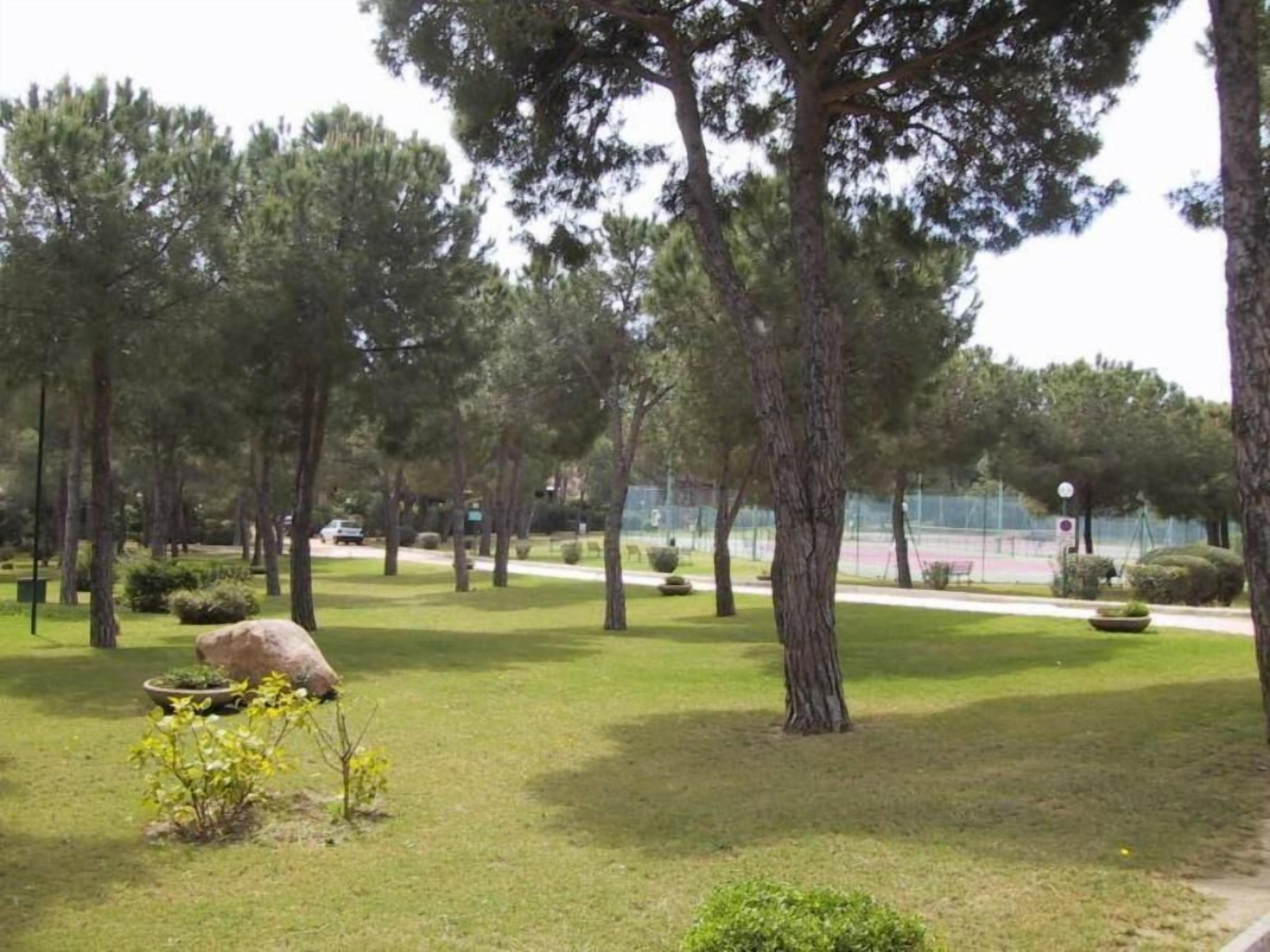 A park with trees, a tennis court, and a pathway.
