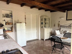 A kitchen with a refrigerator, a sink, and a stove. There is a dining area with a table and chairs.