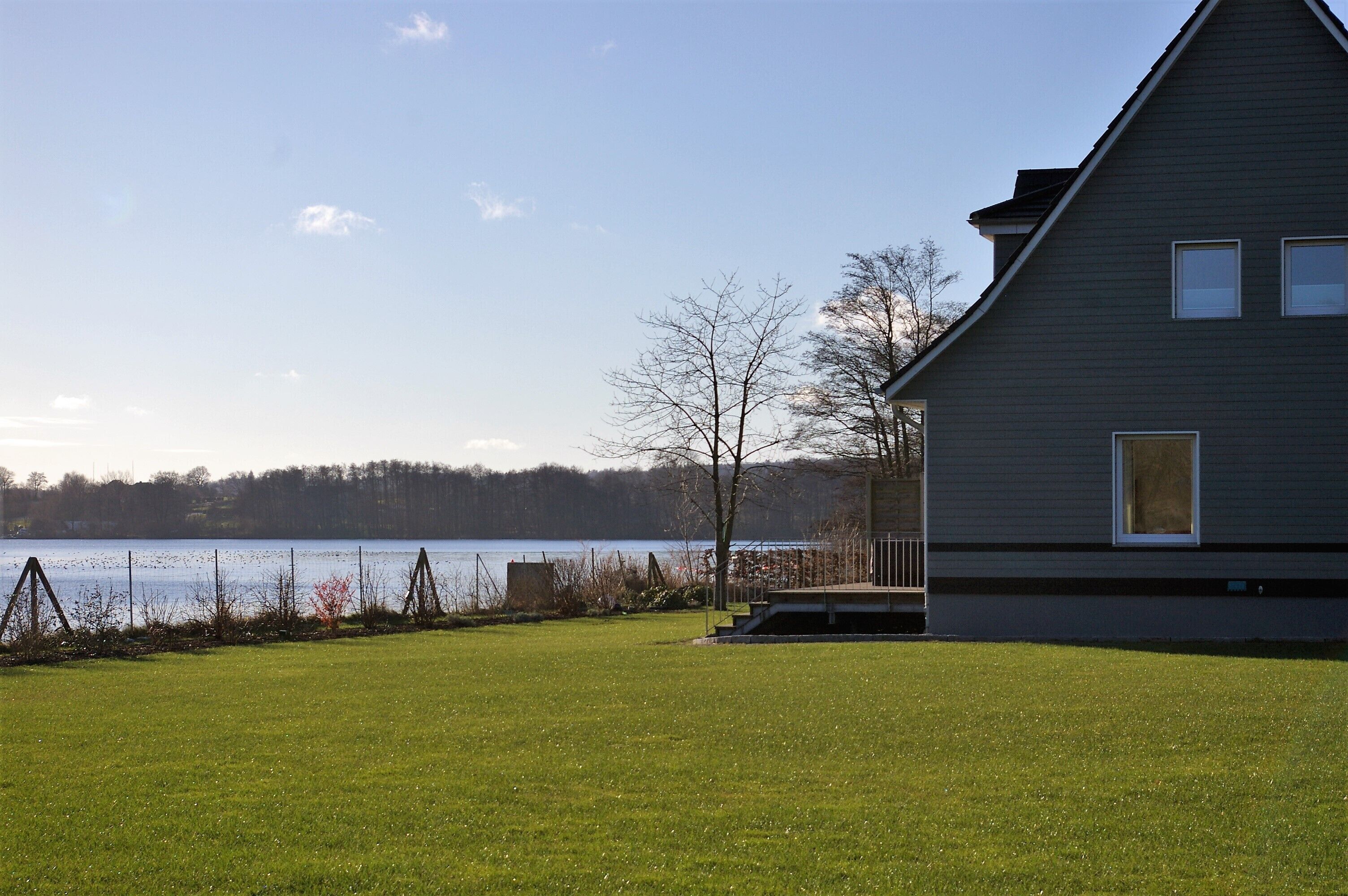 A house with a large lawn and a view of a lake.