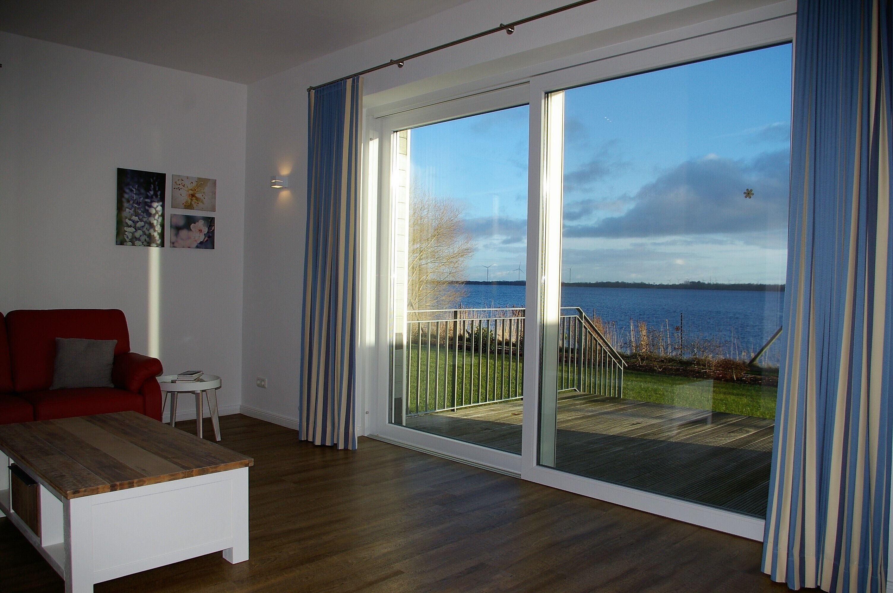 A spacious living room with a large sliding glass door leading to a deck with a view of the water.