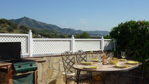 An outdoor patio with a table set for dining, a grill, and a view of mountains. - Spacious Villa With Sea And Mountain Views Very Close To The Communal Pool (Nerja)