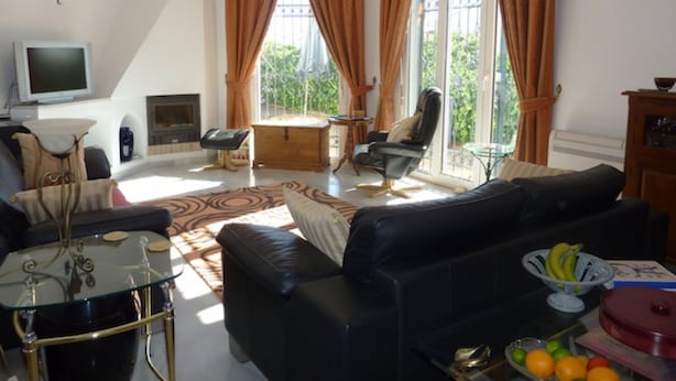 A living room with a black leather sofa, a glass coffee table, a wooden cabinet, and a television on a stand. - Spacious Villa With Sea And Mountain Views Very Close To The Communal Pool (Nerja)