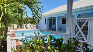 A pool area with a white fence, lounge chairs, and a covered seating area. - Featured in Times Travel 50 Best Caribbean Villas Nov '14 (Hamilton Estate)