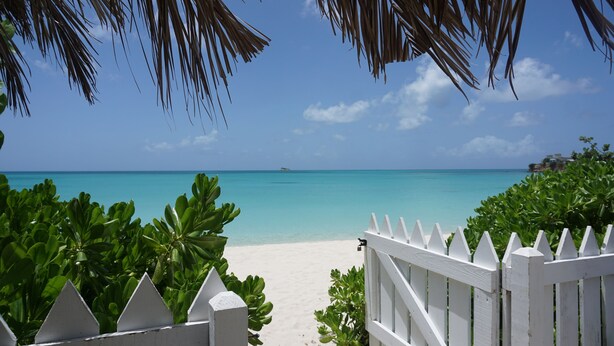 A beach view with a white fence and lush greenery. - Featured in Times Travel 50 Best Caribbean Villas Nov '14 (Hamilton Estate)