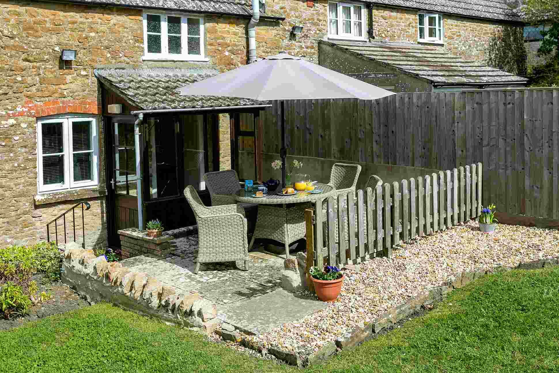 A patio with a table and chairs, a wooden fence, and a stone wall.