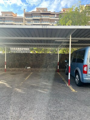 A parking area with a covered section labeled 'SUPERMARKE' and a stone wall.
