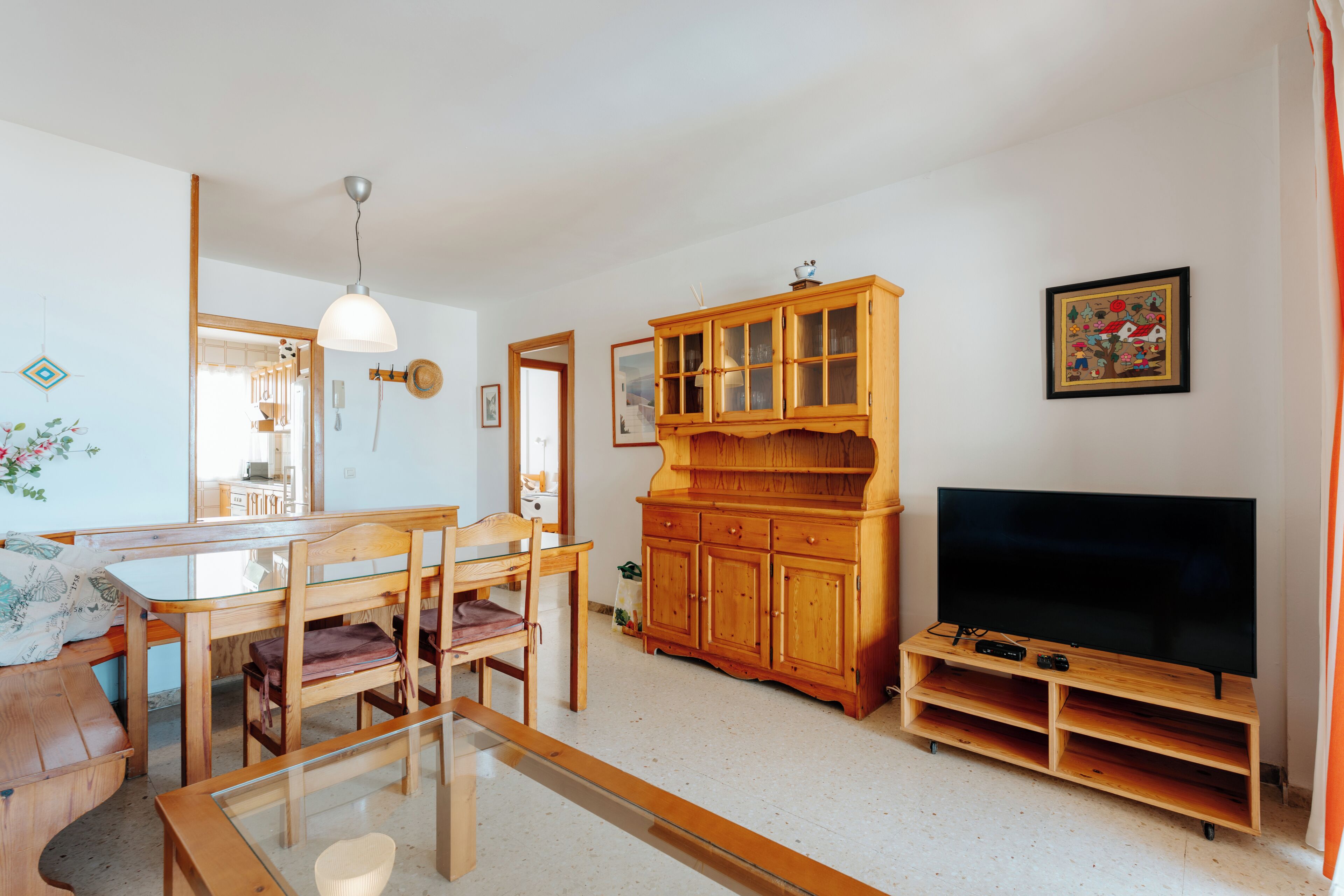 Ein Wohnzimmer mit Essbereich, Holzmöbeln, einem Fernseher und einem Schrank.