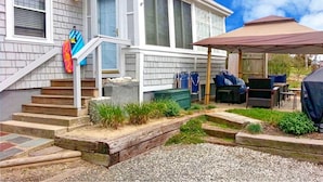 A residential house with a covered patio, a set of stairs leading to a front door, and a small garden area.