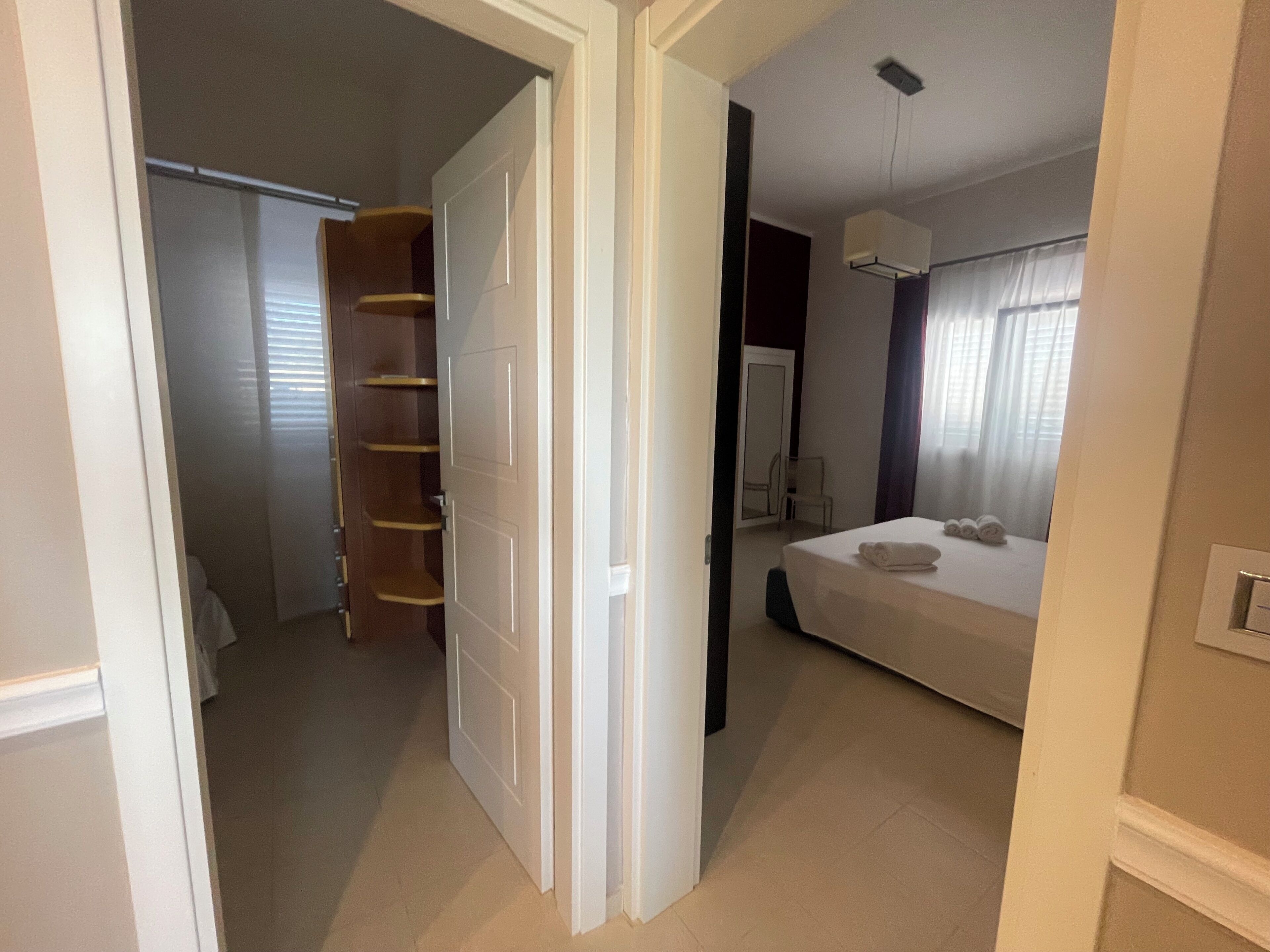 Ein Schlafzimmer mit einem Bett, einem Nachttisch, einem Kleiderschrank und einem Spiegel.