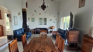 Een ruime woonkamer met een houten eettafel en stoelen, een bank en een televisie.