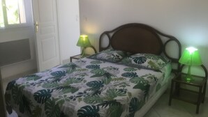Ein Schlafzimmer mit einem Bett, zwei Nachttischen, einer Tür und zwei Wandleuchten.