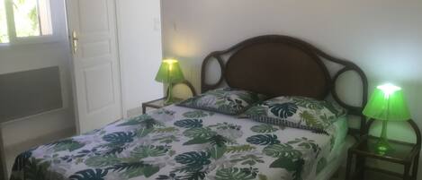 A bedroom with a bed, two nightstands, a door, and two wall-mounted lights.