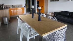 Una cucina moderna con mobili arancioni, un tavolo da pranzo in legno e sedie bianche.