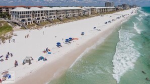 Un hotel frente a la playa con varios balcones, una playa de arena y vistas al océano.