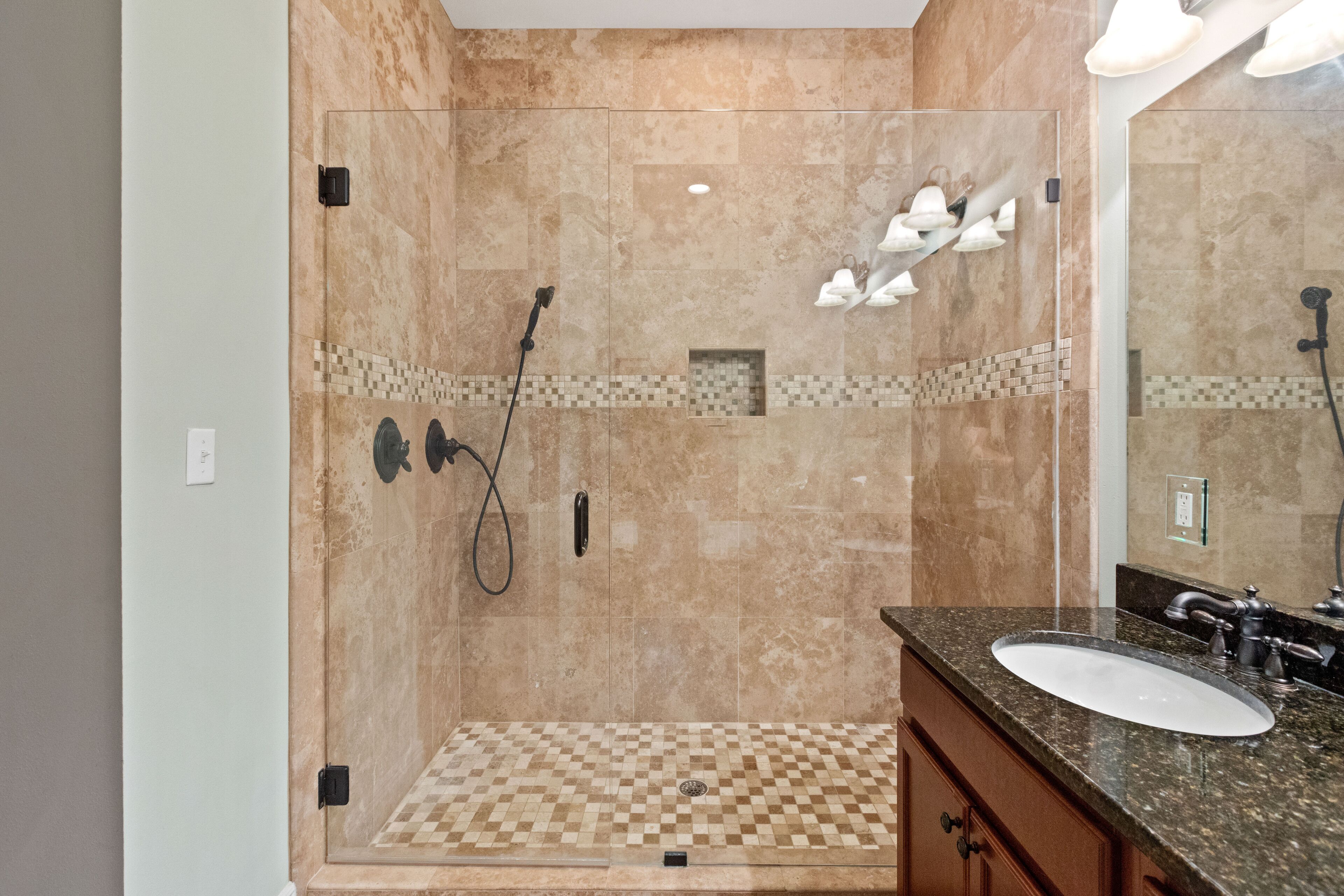 A modern bathroom with a walk-in shower, a sink, and a mirror.