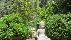 A stone Buddha statue in a garden with dense greenery and wooden structures. - Detached villa with good amenities, private pool, close to Aix en Provence (Coudoux)