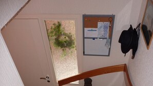 Eine Treppe mit Holzbalkon und Teppichstufen, die zu einer Tür führen.