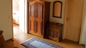 Ein Zimmer mit einem Holzschrank, einer Kommode, einem Spiegel und einer Tür.